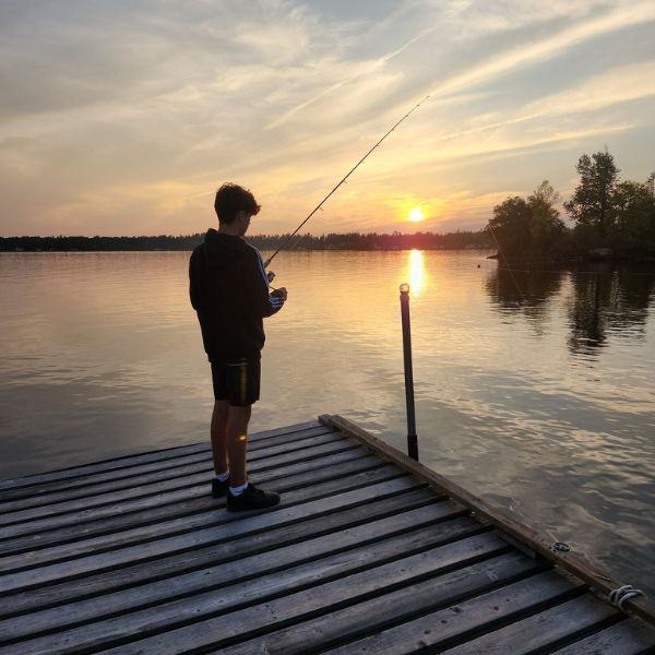 A child fishing off the dock during sunset and enjoying family fun.