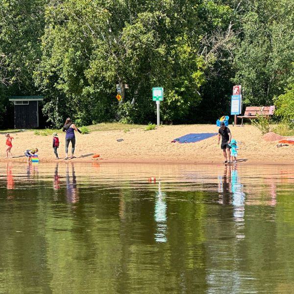 The beach at Inverness Falls Resort with people and kids playing on the sand and in the water, highlighting the family fun that can be discovered here.