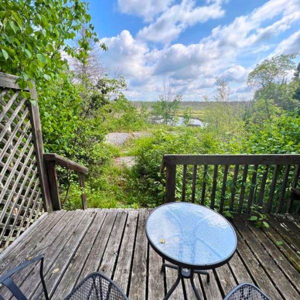 Patio chairs and table overlooking the stream view and green scenery.