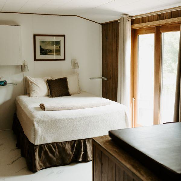 Inverness Falls Resort bedroom with a queen sized bed, hot tub, and view of the outdoors.