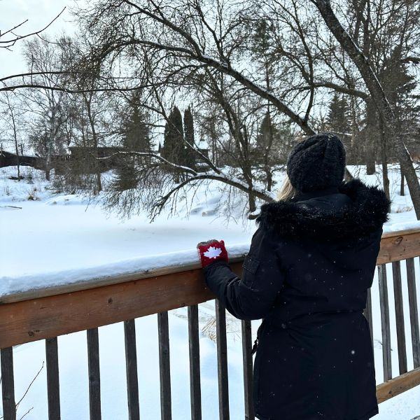 A woman standing at the bridge overlooking the frozen stream, enjoying personal retreats.