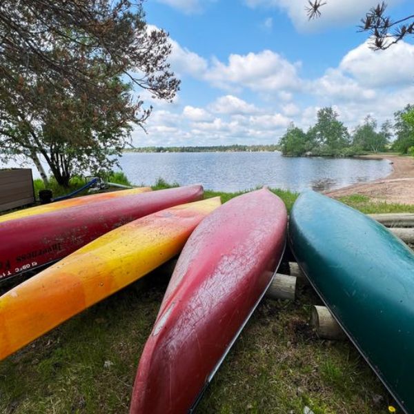 Four canoes piled together along Brereton Lake, showcasing that Inverness offers free use of outdoor equipment for guests.
