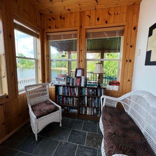 Sunroom with cozy seating and book case.